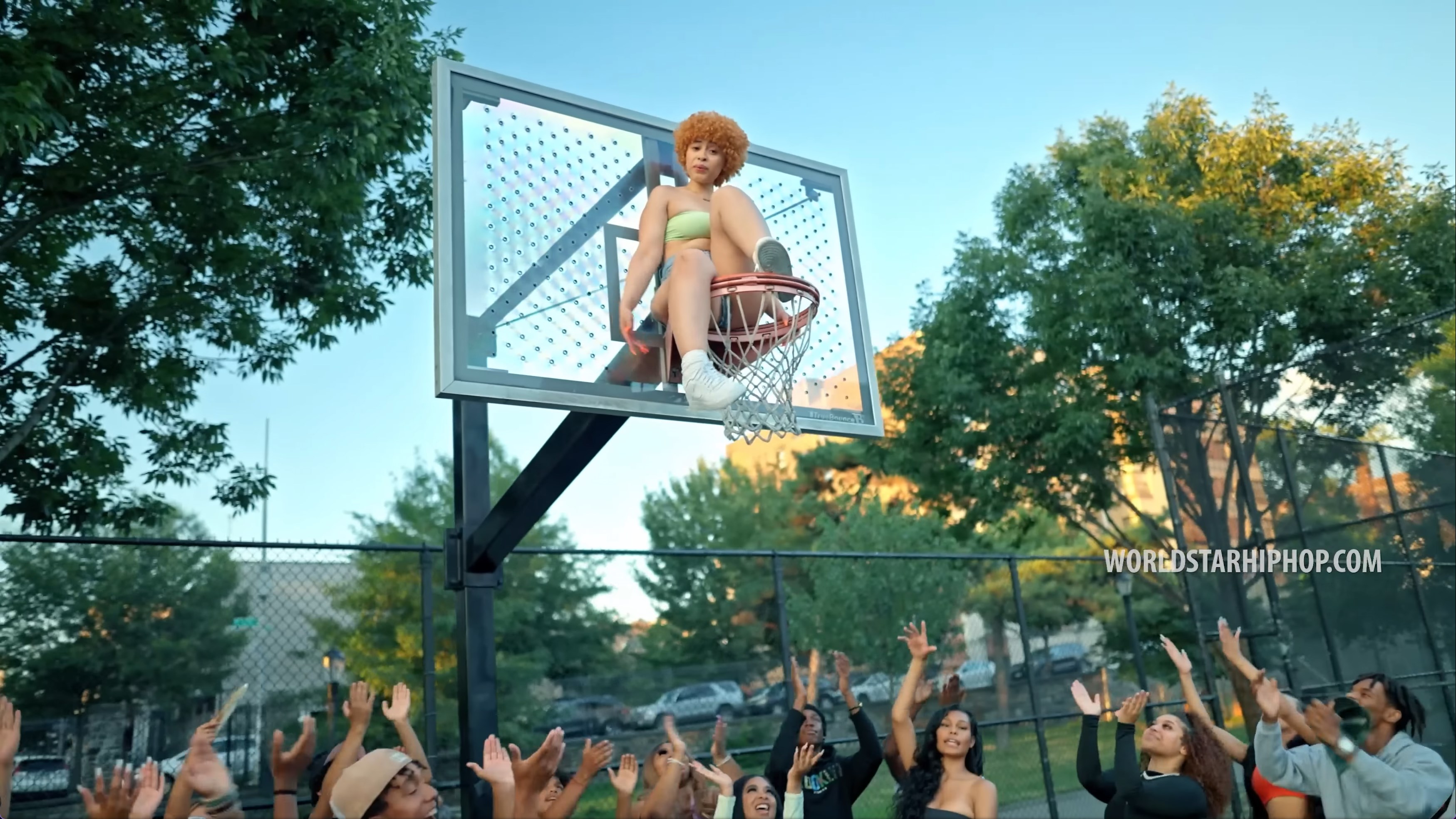 Ice Spice sitting on a basketball hoop in the 